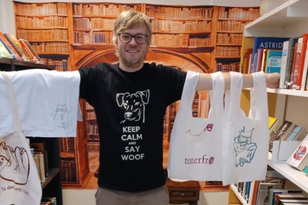T-skjorter og bærenett med vinyltrykk, vist fram av en ansatt på biblioteket. Foto.