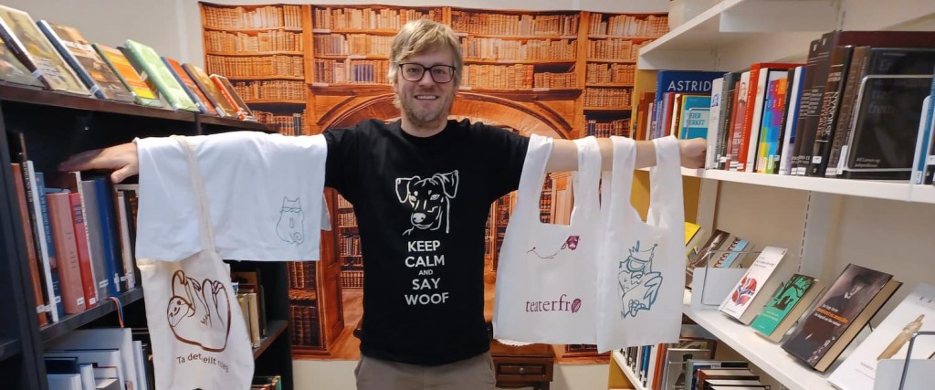 T-skjorter og bærenett med vinyltrykk, vist fram av en ansatt på biblioteket. Foto.