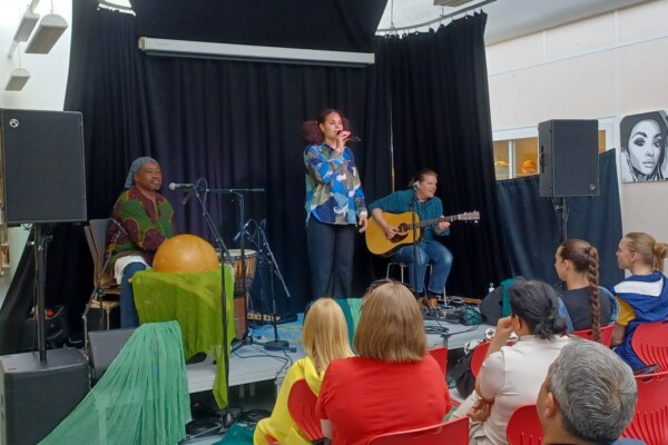 Foto: To musikere (gitar og perkusjon) og en sanger foran publikum.