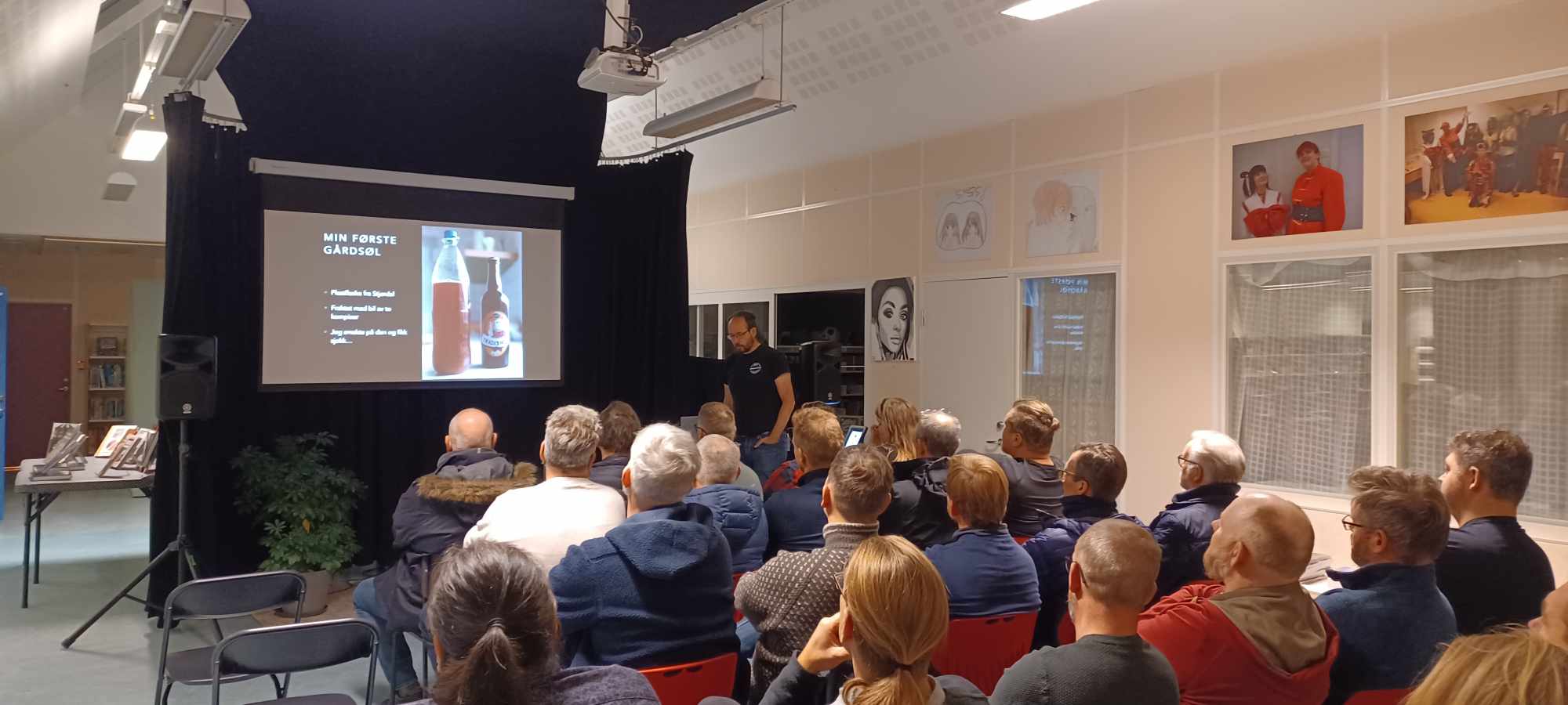 Foto av publikum som ser på en PowerPoint-presentasjon.