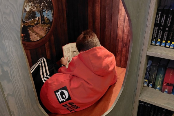 Foto av gutt som leser en bok i en lesehule