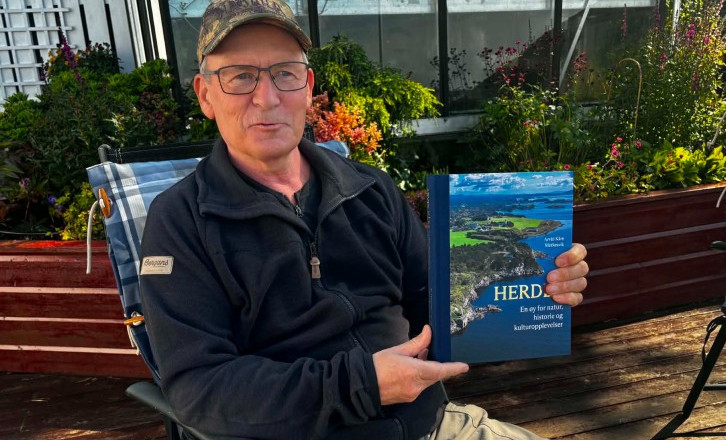 Foto av Arvid Kåre Merkesvik som viser frem boken sin "Herdla".