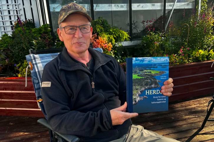 Foto av Arvid Kåre Merkesvik som viser frem boken sin "Herdla".